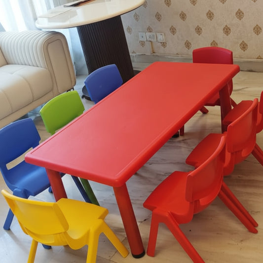 Colorful children's table and chairs in a room with a sofa and patterned wallpaper.